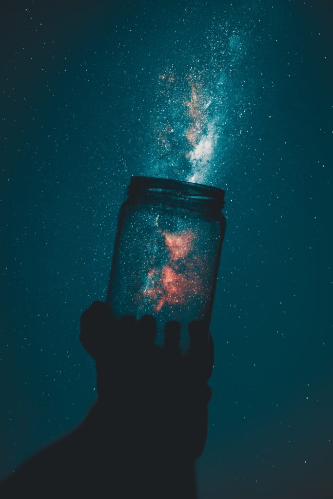 A person showcasing a branded jar with the milky way in the background.