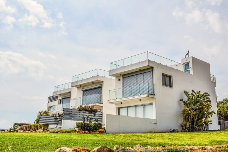 A white house on a grassy hill featuring the best real estate marketing agency.