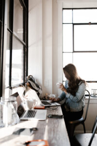 A woman enhancing local SEO for small businesses in Portland Metro with a laptop and a cup of coffee.