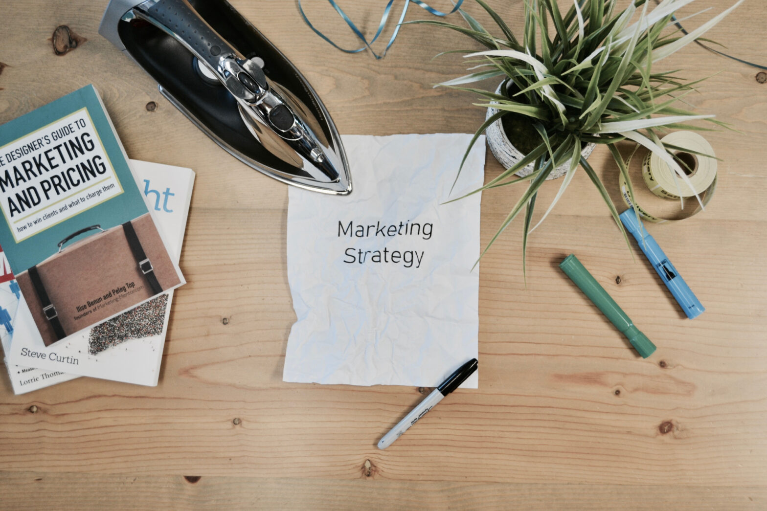 A note with the word "marketing strategy" on it sits on a wooden table, highlighting online presence.