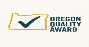 Outline of the state of Oregon with a large check mark inside, next to bold text reading "Oregon Quality Award"—a perfect emblem for small businesses or any branding company in Oregon. White background emphasizes clarity and prestige.